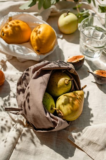 A tasteful arrangement of fresh fruits in eco-friendly linen bags, basking in natural sunlight.